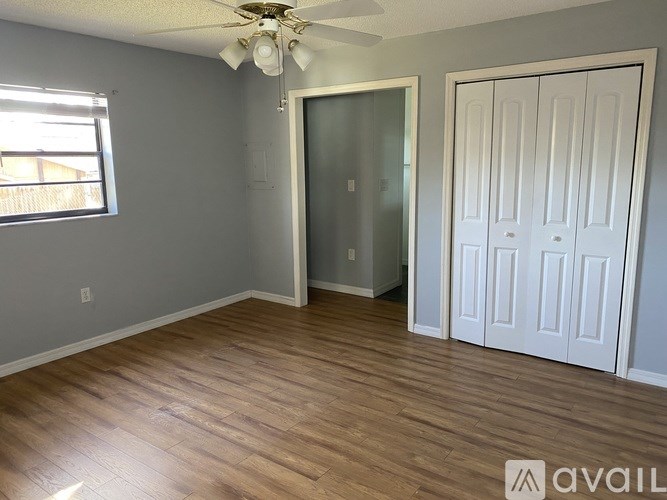 A room with a ceiling fan and wooden flooring.