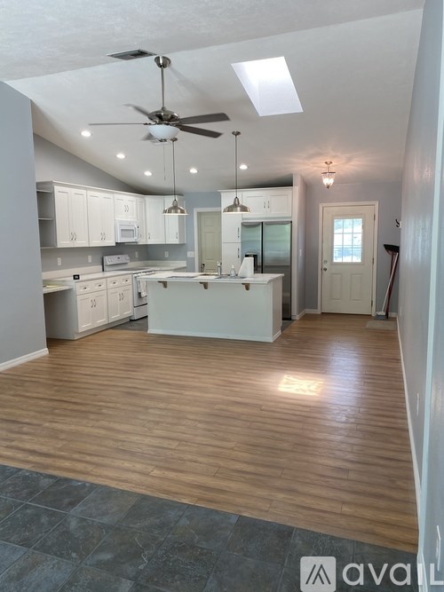 A kitchen with wooden floors and a ceiling fan.