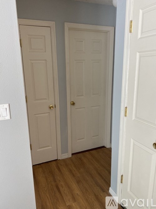 A hallway with two doors and a light switch on the wall.