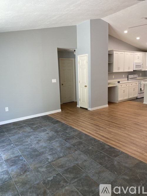 A kitchen area with a tile floor leading to a white door.