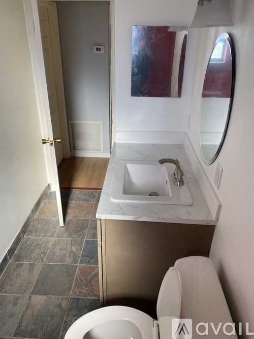 A bathroom with a toilet, sink, and mirror.