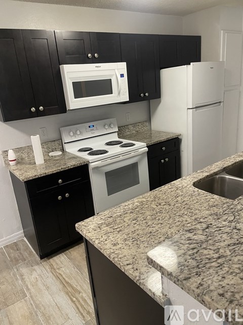 A kitchen with black cabinets and a granite countertop.
