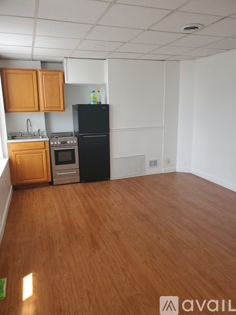 A kitchen with wooden cabinets and a black refrigerator.