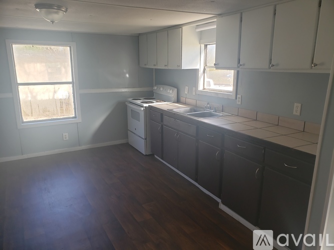 A kitchen with white cabinets and a wooden floor.