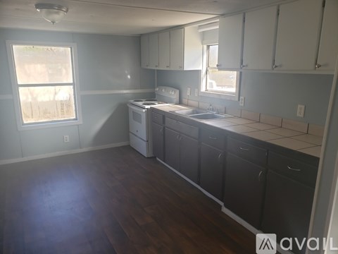 A kitchen with white cabinets and a wooden floor.