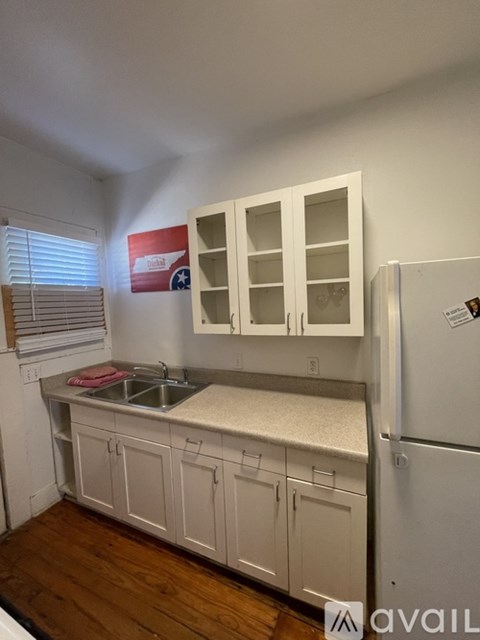 A kitchen with white cabinets and a refrigerator.