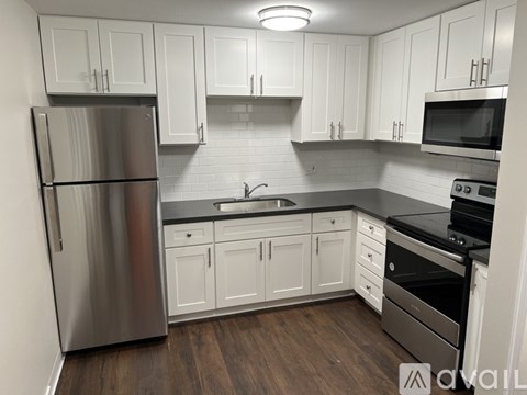 A kitchen with white cabinets and a stainless steel refrigerator.