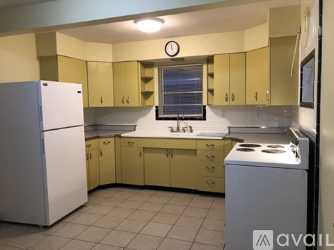 A kitchen with yellow cabinets and a white refrigerator.