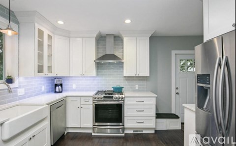 A modern kitchen with white cabinets and stainless steel appliances.