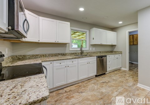 A kitchen with granite countertops and white cabinets.