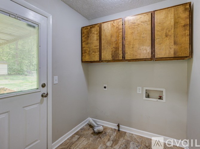 A room with a white door and wooden cabinets.