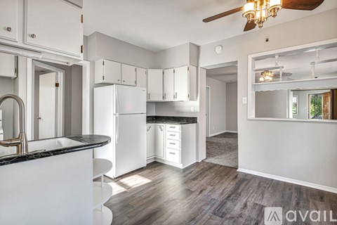A kitchen with white cabinets and a black countertop.