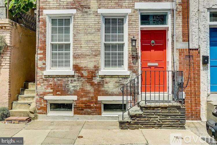 A red door is on the front of a brick house.