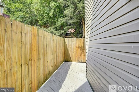 A wooden deck with a grey wall and trees in the background.