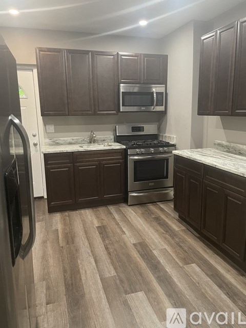 A kitchen with dark wood cabinets and a refrigerator.