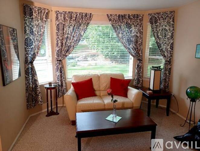A living room with a couch, a table, and a window with curtains.