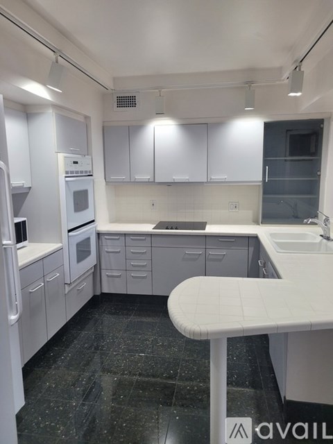 A kitchen with white cabinets and black countertops.