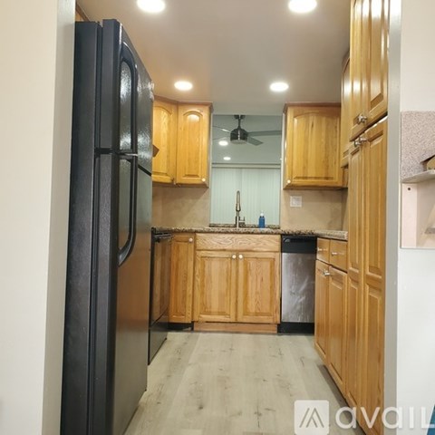 A kitchen with wooden cabinets and a black refrigerator.