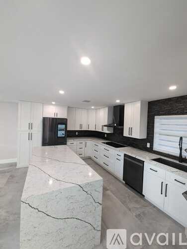 A modern kitchen with white cabinets and a marble countertop.