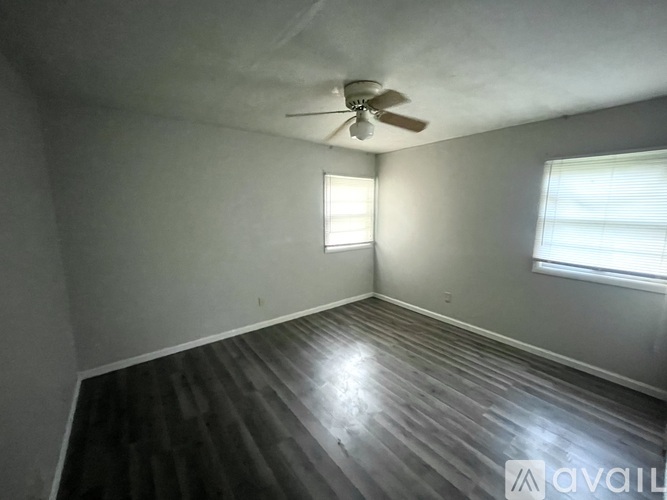 A room with a ceiling fan and wooden flooring.