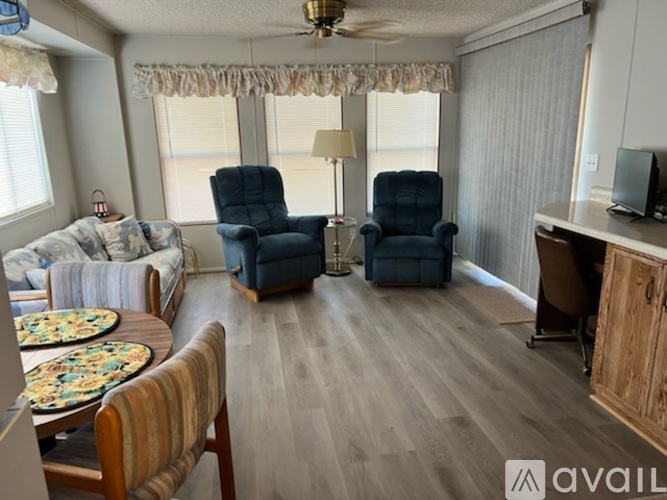 A living room with a sofa, two chairs, a table, and a television.