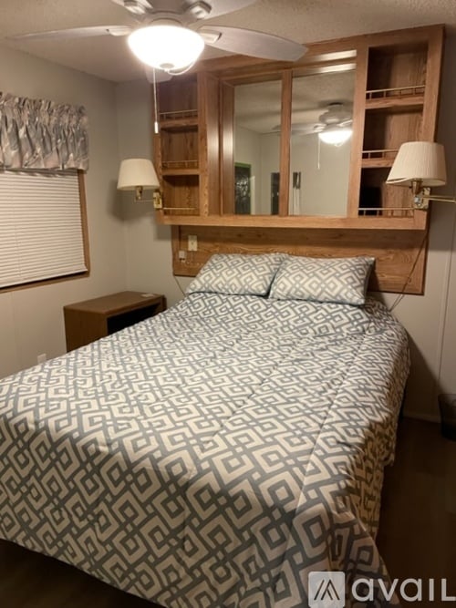 A bedroom with a bed, nightstand, and a mirror above the bed.