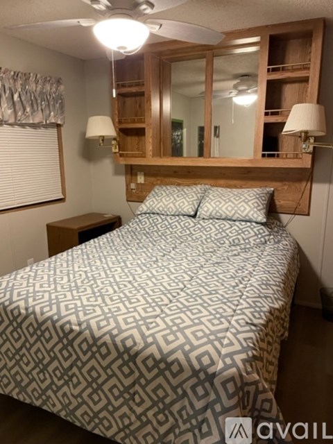 A bedroom with a bed, nightstand, and a mirror above the bed.