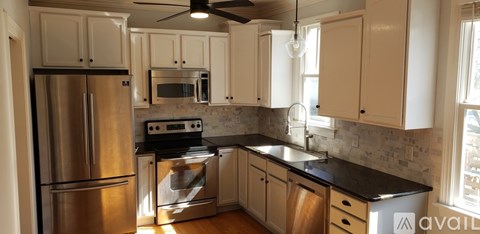 A kitchen with a stainless steel refrigerator and a black countertop.