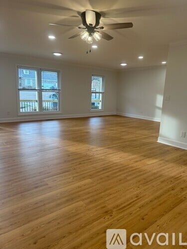 A spacious room with wooden flooring and a ceiling fan.
