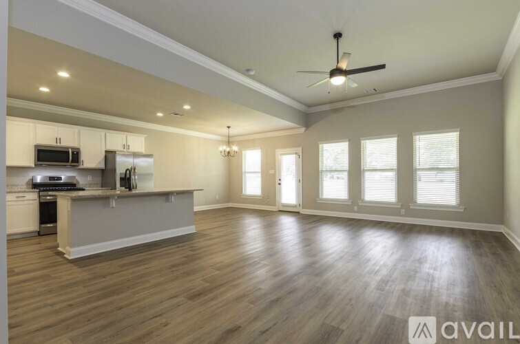 A spacious kitchen and living room with wood flooring and a ceiling fan.