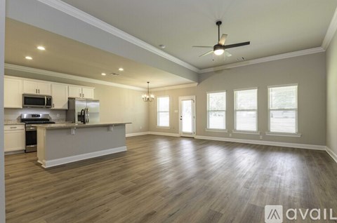A spacious kitchen and living room with wood flooring and a ceiling fan.