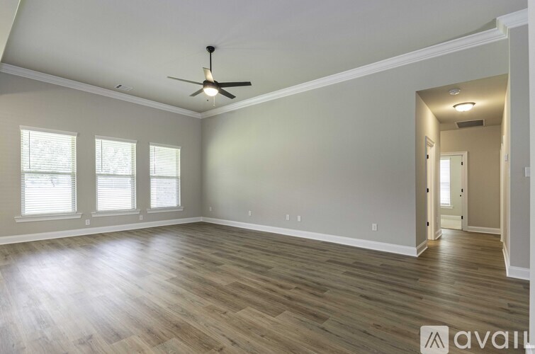 A spacious room with a ceiling fan and hardwood flooring.