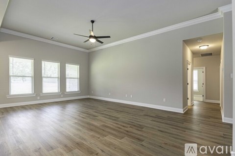A spacious room with a ceiling fan and hardwood flooring.