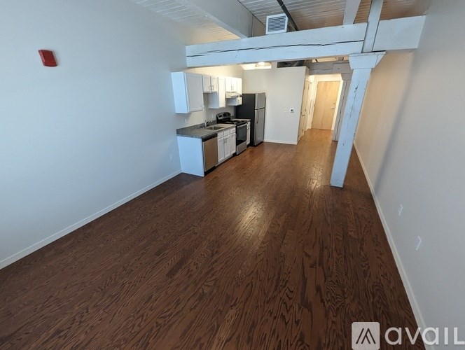 A kitchen area with wooden flooring and white walls.
