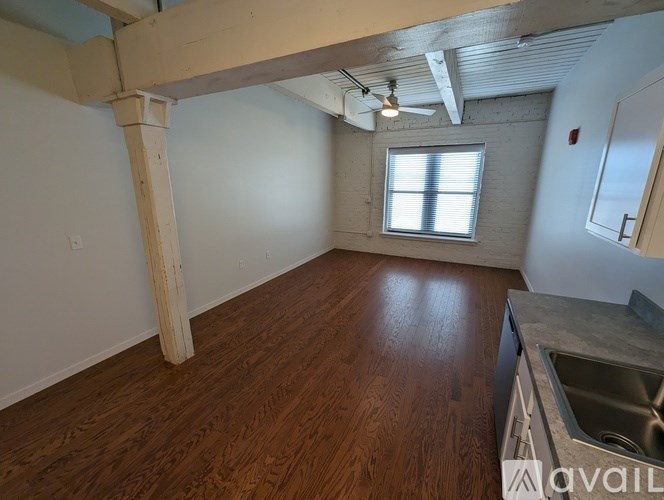A room with wooden floors and a window with blinds.