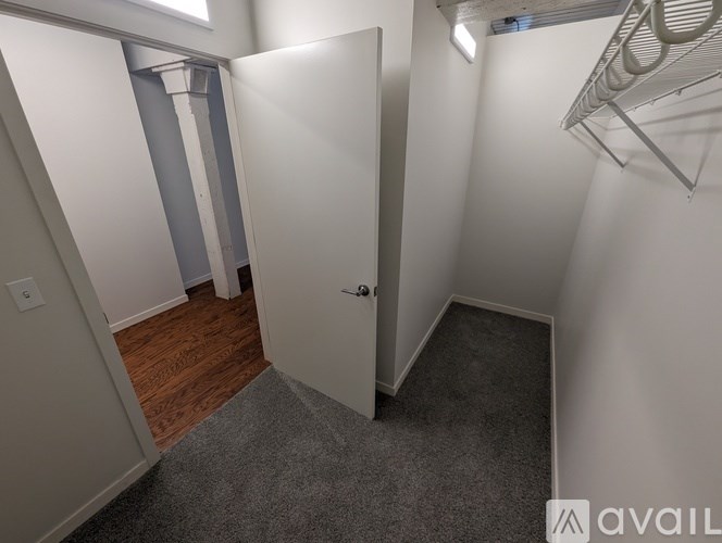 A room with a white door and a grey carpet.