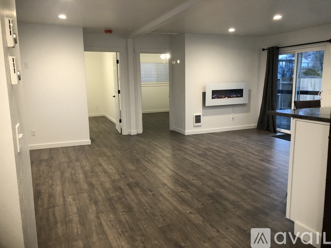 A spacious room with wood flooring and white walls.
