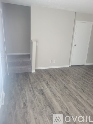 A room with a grey carpet and wooden flooring.