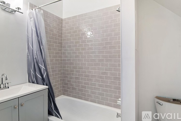 A bathroom with a white tub and grey tiles.