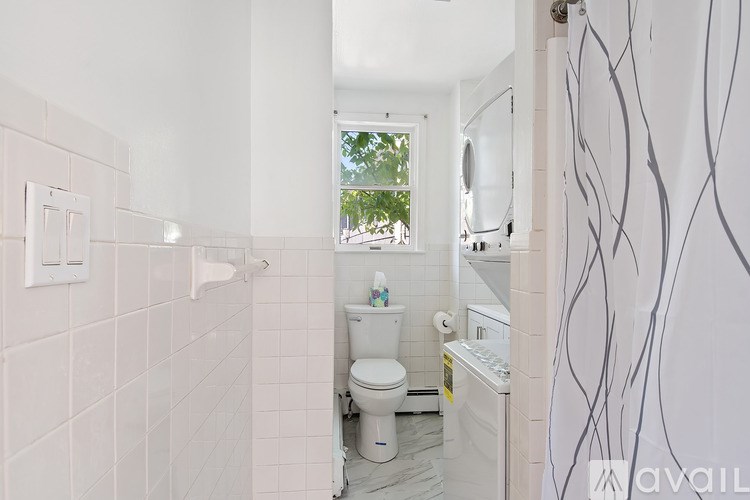 A bathroom with a toilet, sink, and a window.