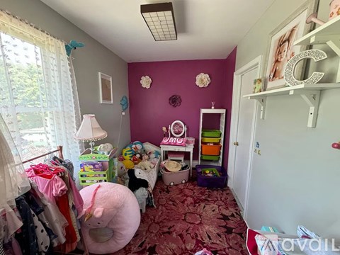 A room with a ceiling fan and a window overlooking a house.