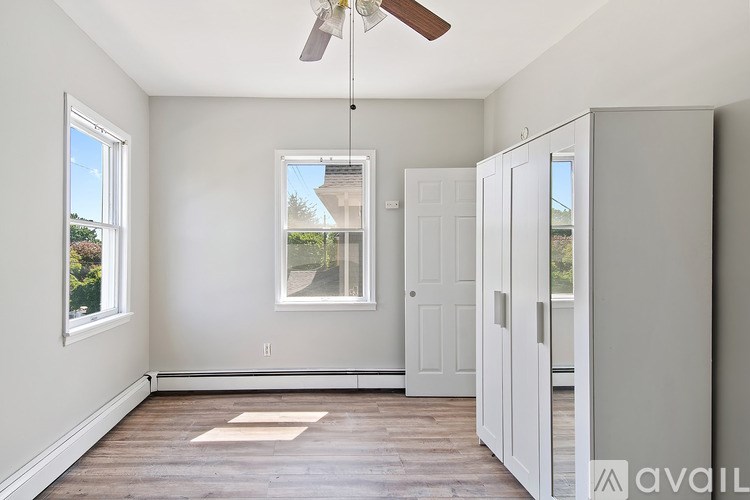 A room with a ceiling fan and a window overlooking a house.