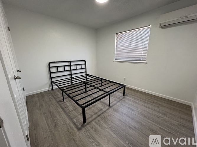 A bedroom with a bed, window, and wooden flooring.