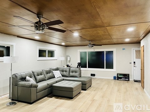 A modern living room with a grey leather sofa and a wooden floor.