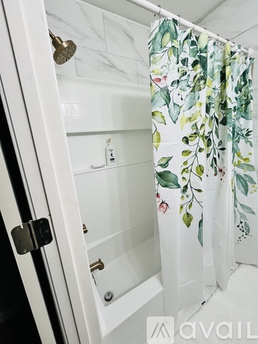 A white bathroom with a floral shower curtain.