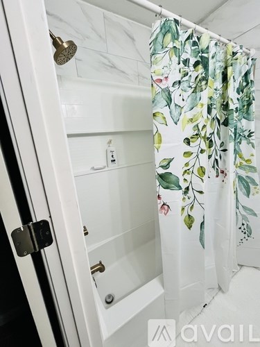 A white bathroom with a floral shower curtain.