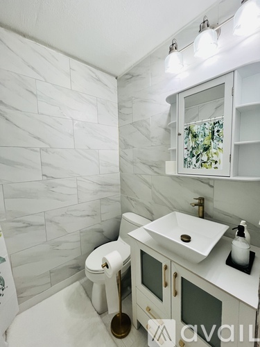 A white toilet with a gold seat sits next to a white sink in a bathroom.