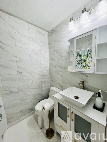 A white toilet with a gold seat sits next to a white sink in a bathroom.