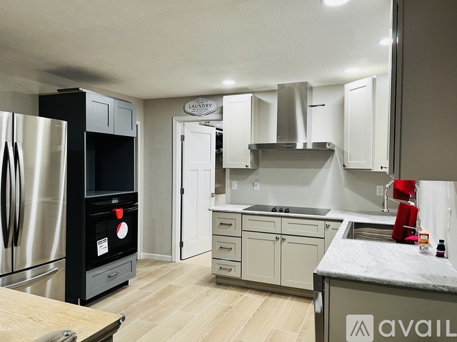 A kitchen with a black fridge and white cabinets.