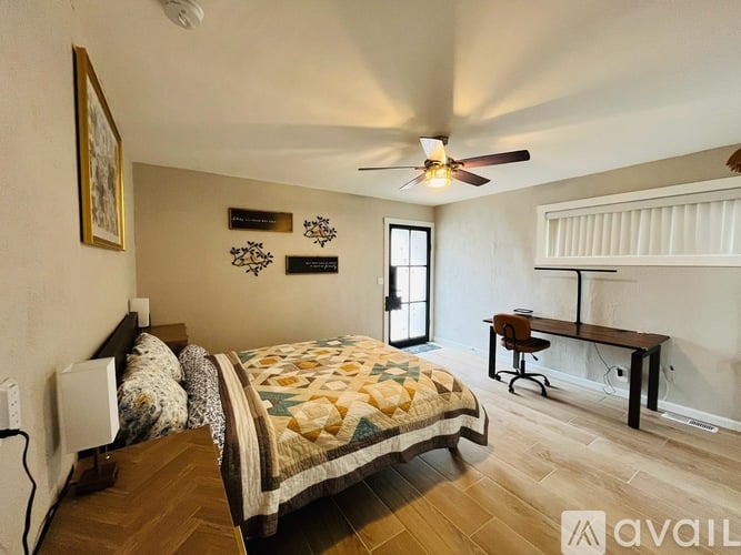 A bedroom with a bed, a ceiling fan, and a window.